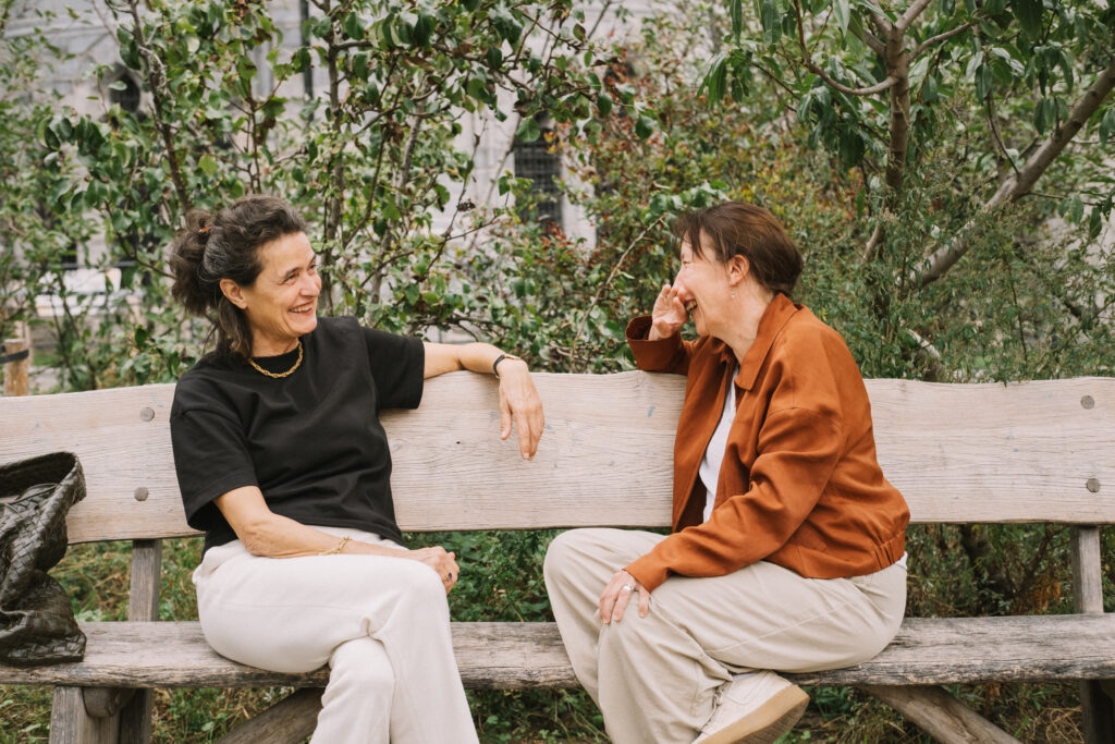 Twee vrouwen in gesprek op een bank in een park.